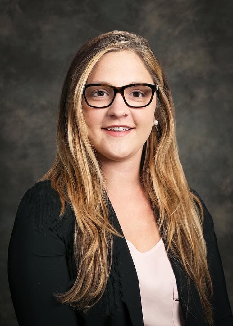 A woman with glasses and long hair wearing a black jacket.