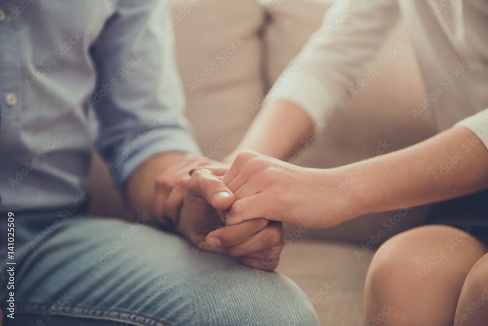 A person holding their hand while sitting on someone 's lap.