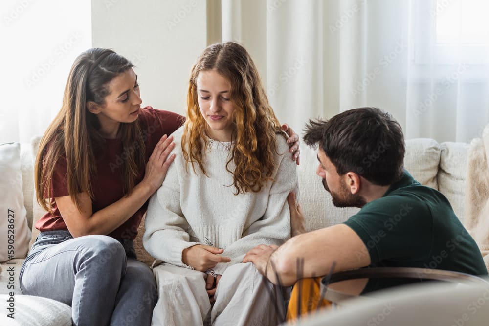 A woman sitting on the ground with two men.